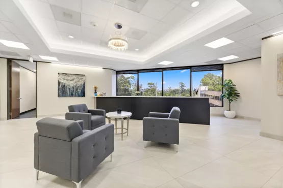 Office lobby seating area with reception desk and large windows