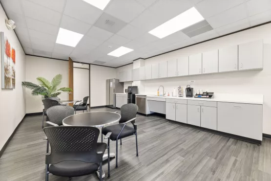 Office kitchenette with cabinets, sink, and seating area