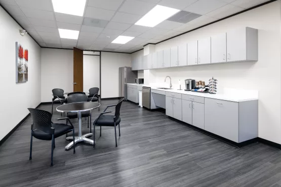 Office break room with a round table, gray cabinetry, and a coffee and kitchen station.