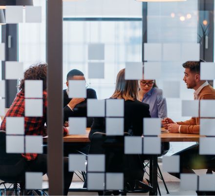Team meeting behind a glass partition in a modern flexible office space.