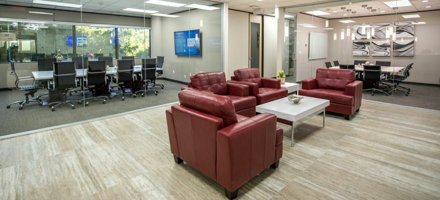 Modern office lobby with red leather chairs and glass-walled conference rooms.