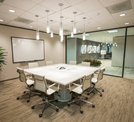 Professional conference room with a large white table and pendant lighting.