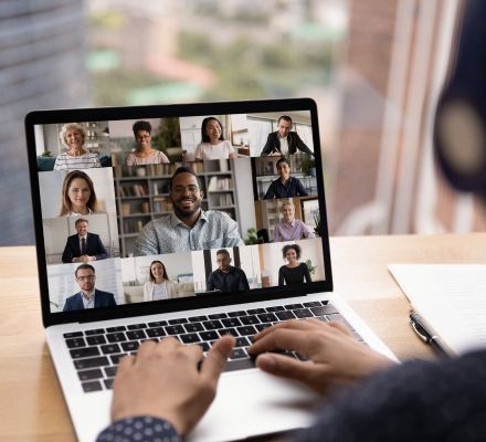 Person joining a video conference call with multiple colleagues on a laptop screen.
